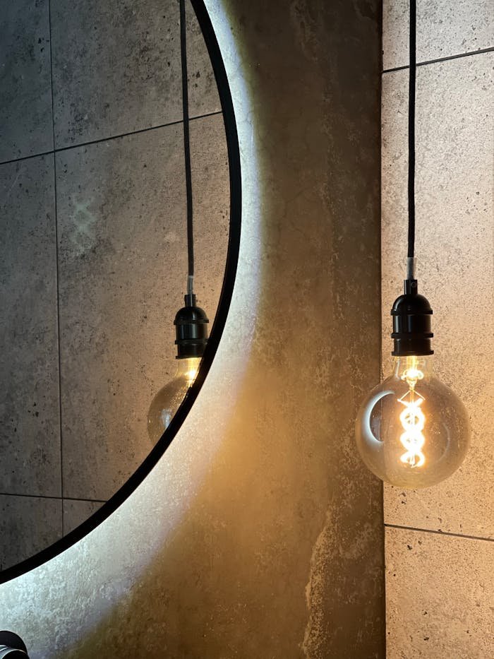 gallery-5 Modern bathroom design featuring a backlit mirror and filament light bulb.