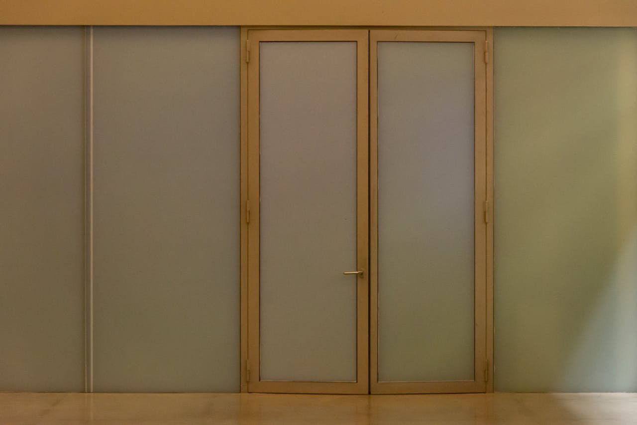 about-01 A minimalist beige door with frosted glass panels creating a modern aesthetic in an indoor setting.