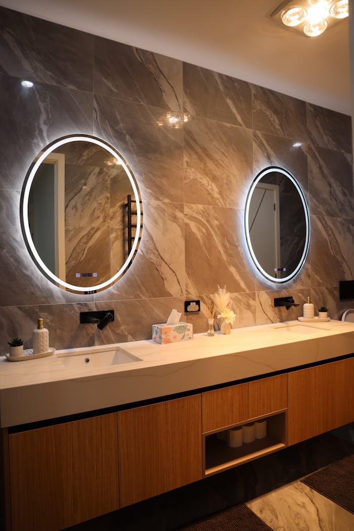 gallery-4 Elegant bathroom interior featuring a double vanity with circular backlit mirrors, sleek design.
