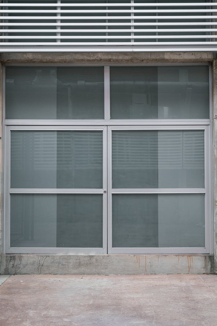 gallery-1 Close-up of a modern glass door with industrial design featuring concrete elements.