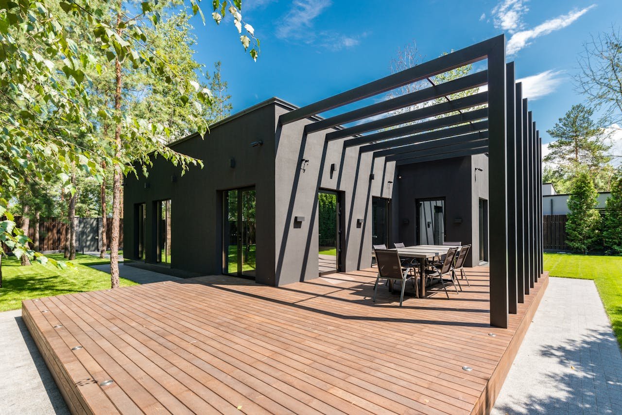 contact-img Stylish outdoor space with wooden deck and dining set, surrounded by lush greenery.